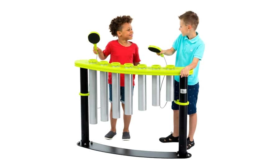 Two children playing outdoor chimes, smiling, holding mallets.